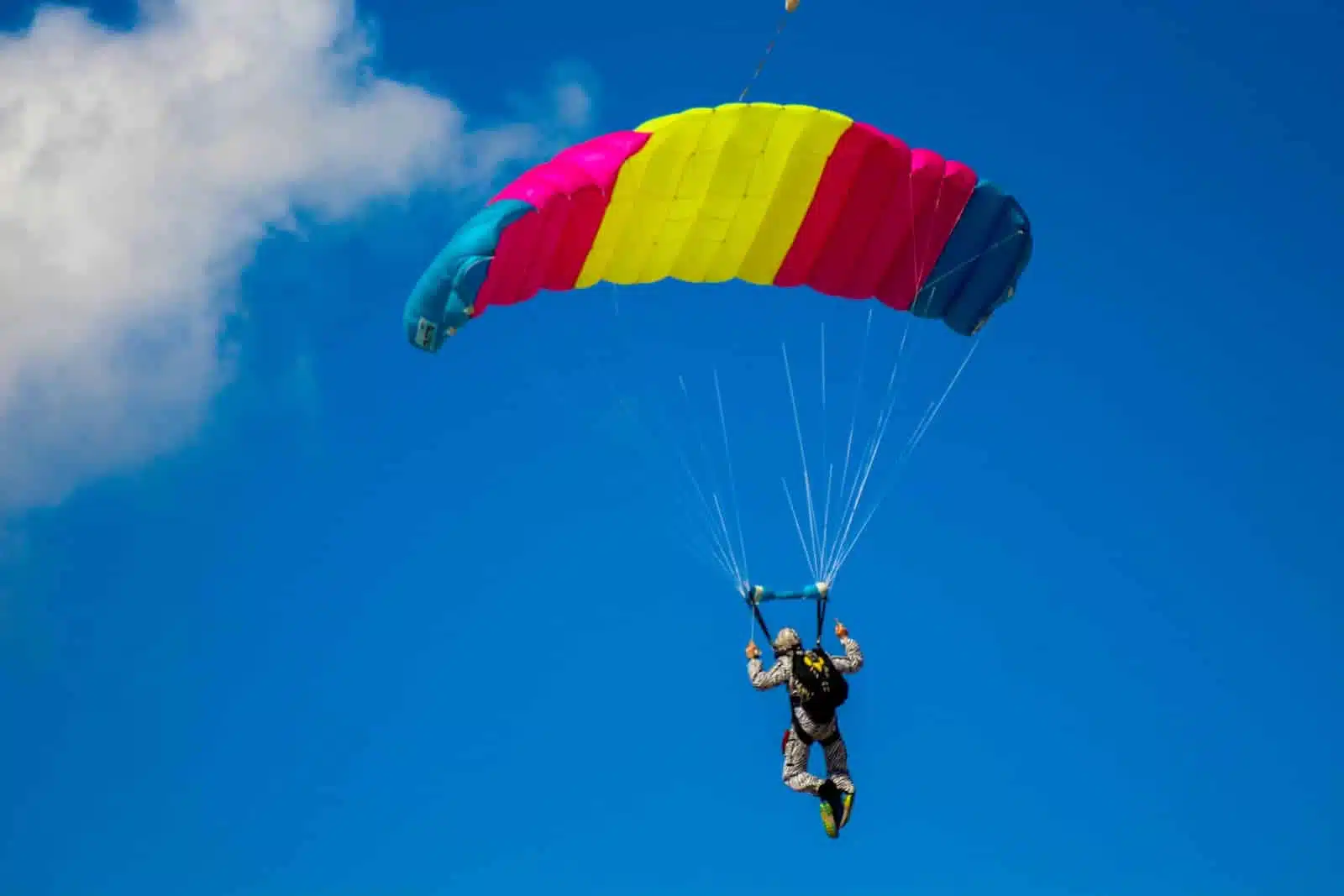 man in black jacket and blue pants riding yellow and red parachute