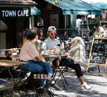 man and woman sitting in front of folding table in front of cafe with green awnings